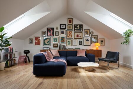 modern eclectic attic living room with dark blue boucle sectional sofa, a gallery wall, muted pink accents