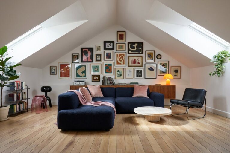 10 Attic Living Room Ideas You’ll Want to Copy modern eclectic attic living room with dark blue boucle sectional sofa, a gallery wall, muted pink accents
