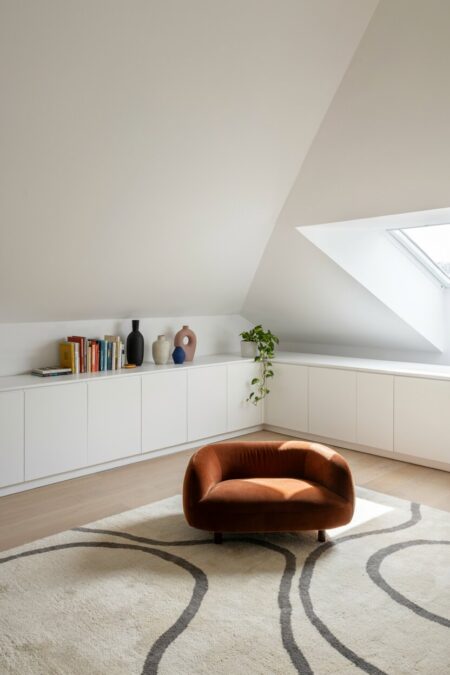 modern eclectic attic living room with white knee wall built-in cabinets and a burnt-sienna velvet lounge chair
