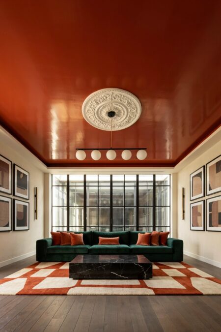 modern maximalist living room has glossy terracotta ceiling with a white medallion, a dark green velvet sofa with plush terracotta-colored silk throw pillows, and a black marble coffee table