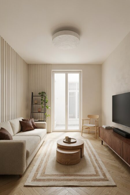 small Japandi living room with light oak herringbone parquet, a dark walnut media console, an ash circular nesting coffee table, and a cream boucle sofa with brown throw pillows