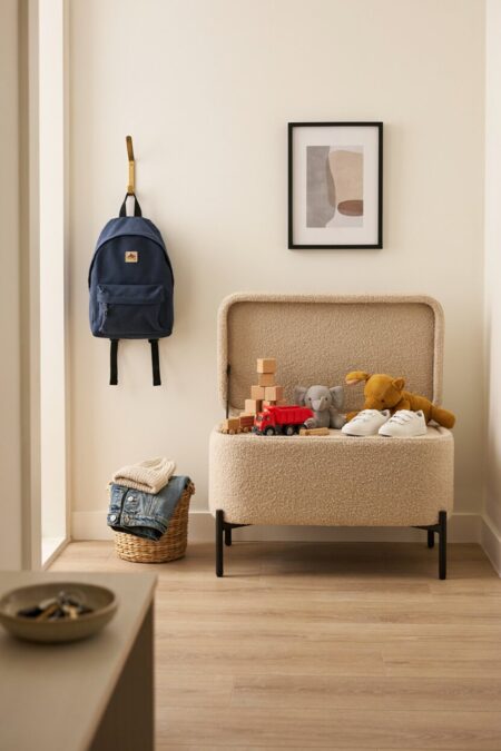 soft storage bench with toys inside and a backpack on the wall hook